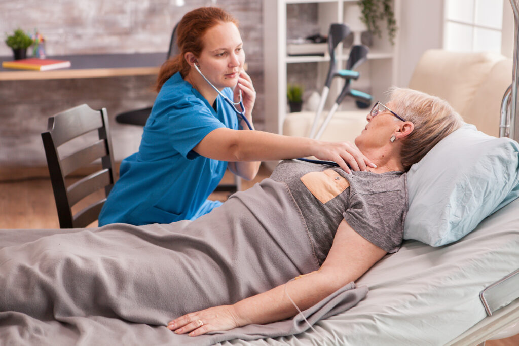 Female doctor using stethoscope to check old woman heart